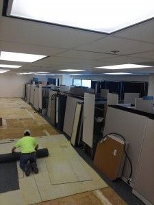 A man is laying carpet in an office.