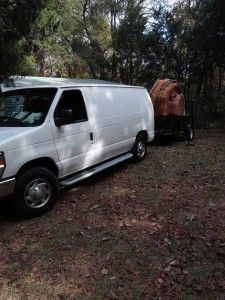 A white van is parked next to a trailer.