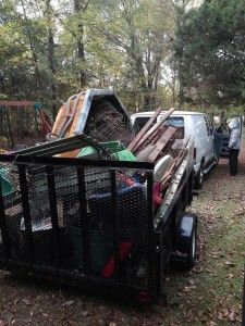 A trailer filled with junk is parked next to a truck.