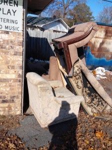 A pile of furniture is sitting in front of a brick building.