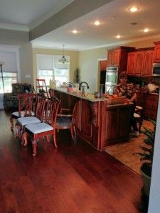 A kitchen with a large island , dining table and chairs.