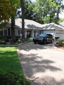 A black car is parked in the driveway of a house.