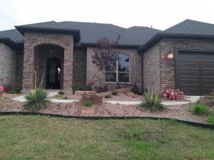 A large brick house with a black roof and a brown garage door.