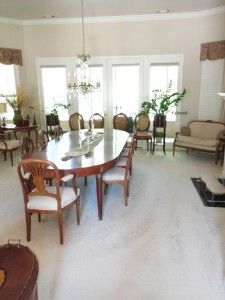 A dining room with a long table and chairs and a couch.