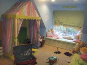 A child 's room with a canopy and a window seat.