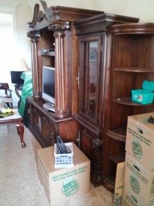 A living room with a large wooden entertainment center and boxes.