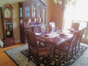 A dining room with a table and chairs and a grandfather clock.