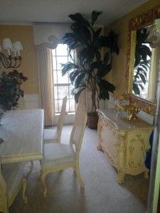 A dining room with a table , chairs , dresser and mirror.