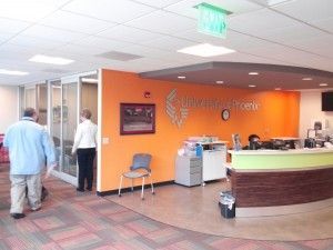 A group of people are standing in a room with an orange wall and a green counter.