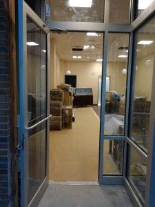 A glass door is open to a room with boxes in it.