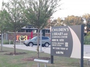 A sign for the children 's library and learning center is in front of a building.