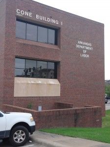 A white truck is parked in front of a large brick building.