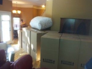 A living room filled with cardboard boxes and a pillow on top of one of them.