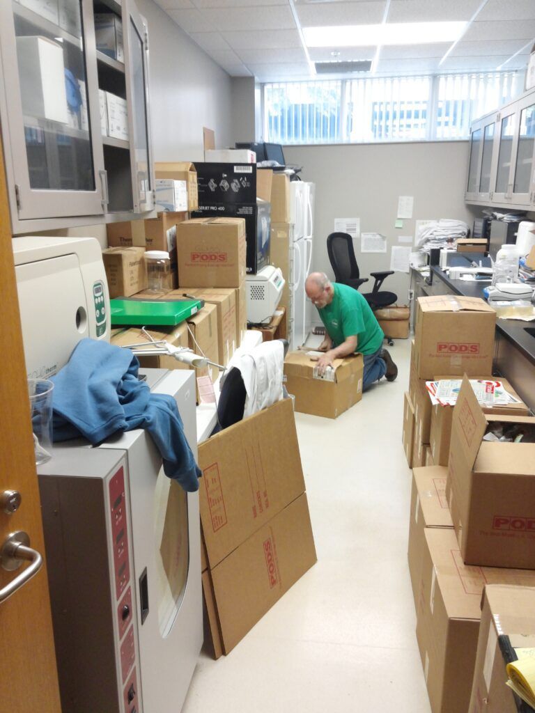 A man in a green shirt is working in a room filled with boxes