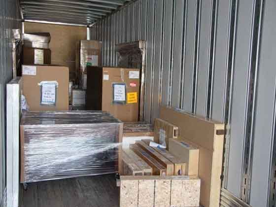 The inside of a shipping container filled with boxes and wood.