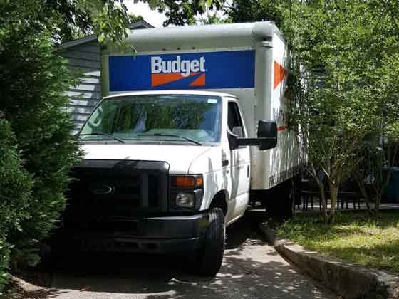 A white budget truck is parked in a driveway
