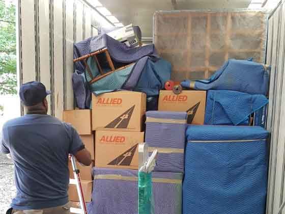A man is loading boxes into a moving truck.