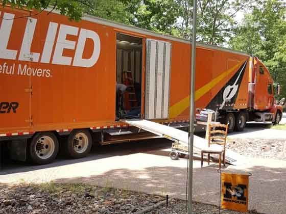 An orange lied moving truck is parked on the side of the road.
