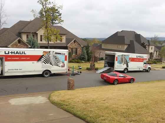 Two u-haul trucks are parked in front of a house.