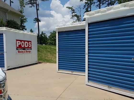 A row of storage containers with blue doors in a driveway.