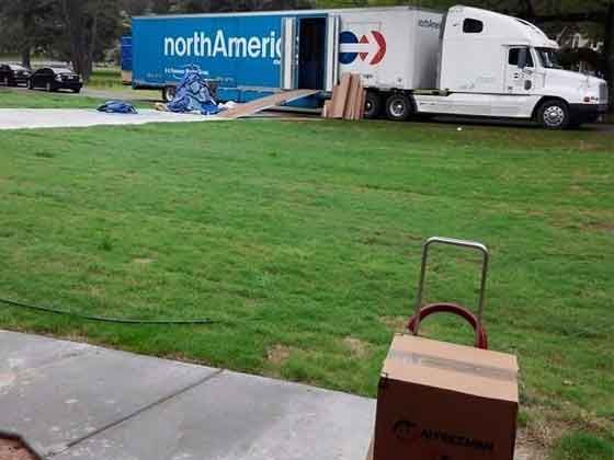 A north america moving truck is parked in a grassy field.