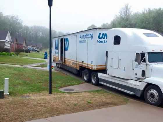 A white truck with a trailer attached to it is parked in a driveway.