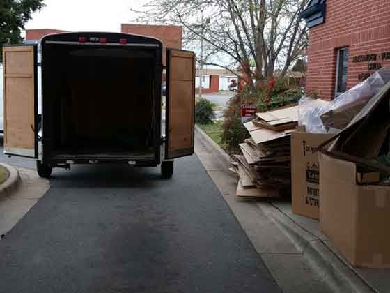 A truck is parked on the side of the road next to a pile of cardboard boxes.