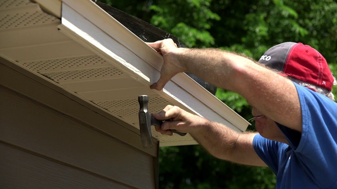 A man is painting a blue wall with a paint roller.