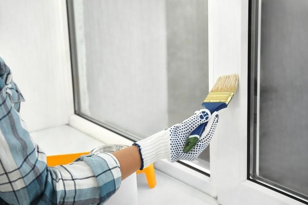 A person is painting a window with a brush.