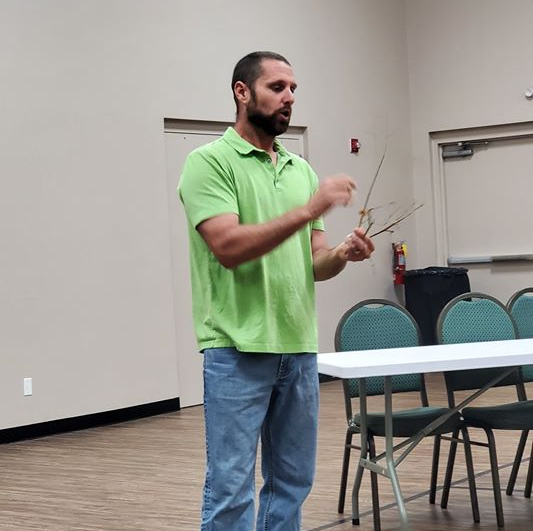 A man in a green shirt is standing in front of a table