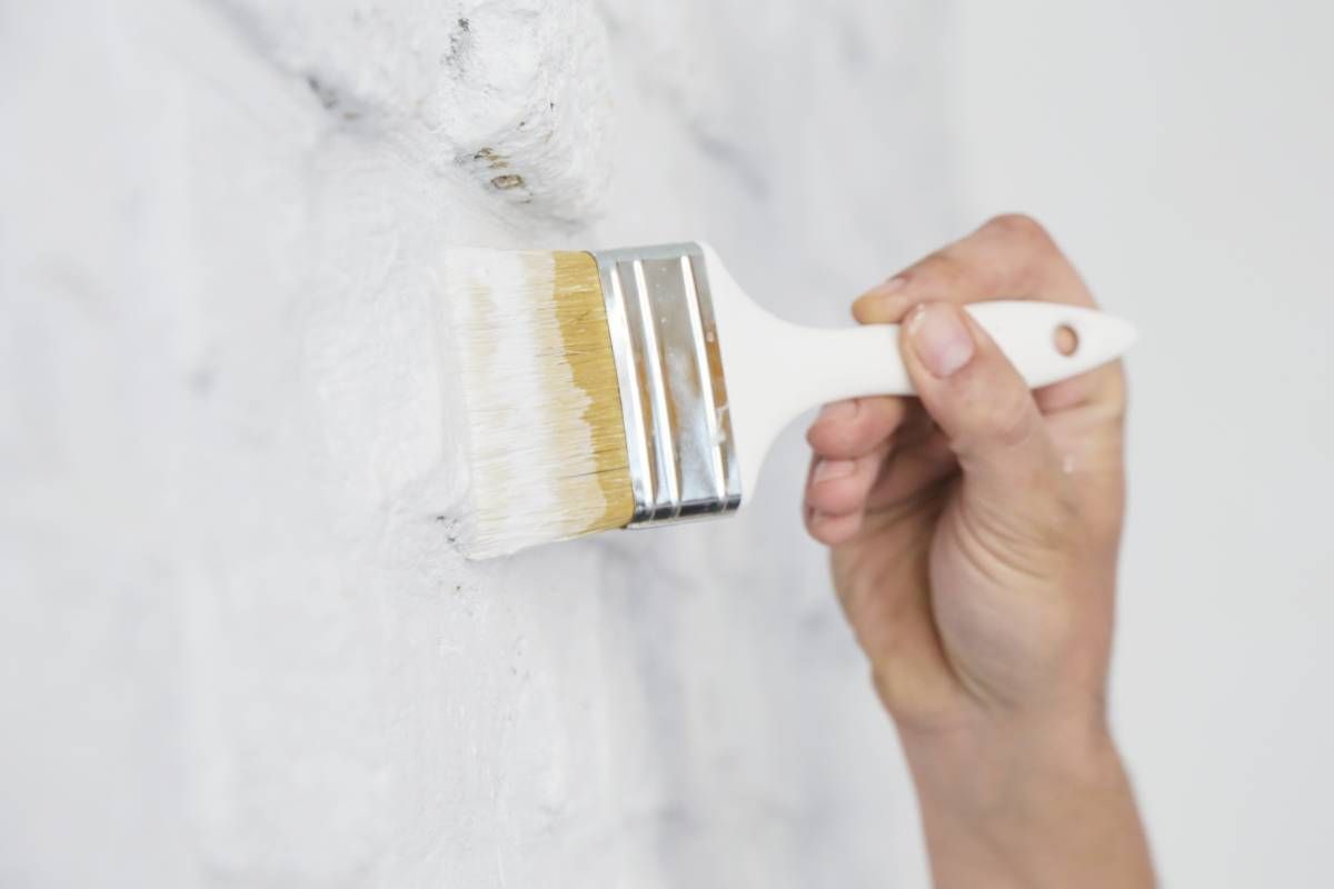 Someone applying a coat of white paint on a brick wall near Bourbonnais, Illinois