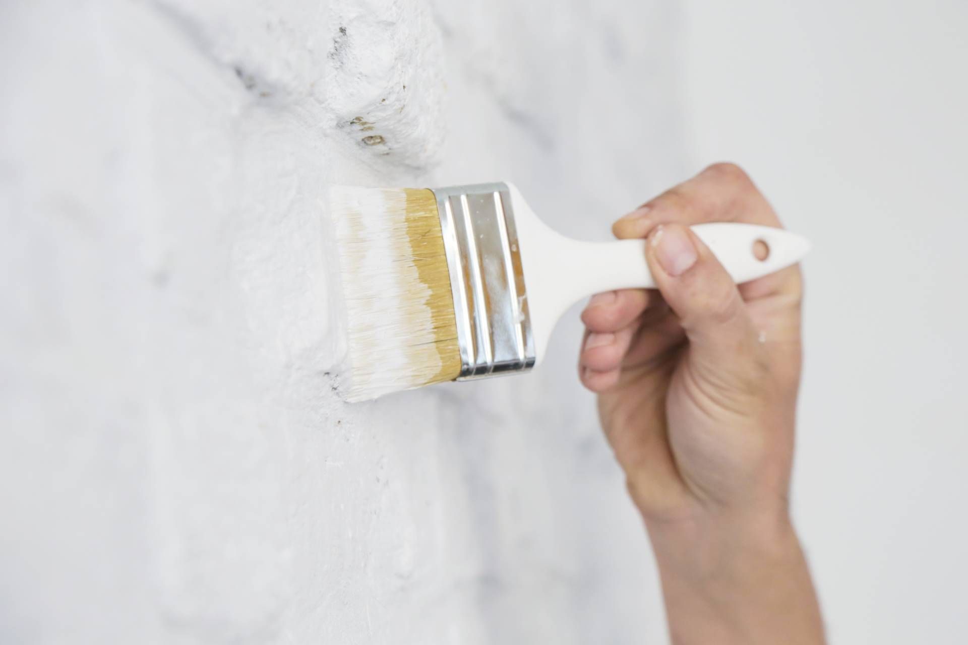 Someone applying a coat of white paint on a brick wall near Bourbonnais, Illinois