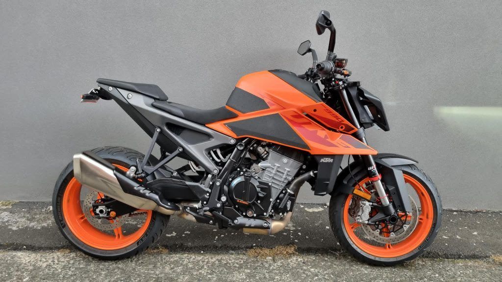 A KTM 890 Duke R motorcycle with orange and black bodywork, orange wheels, and a metallic exhaust parked against a wall.