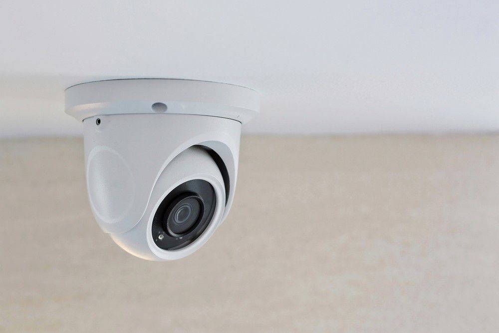 A White Security Camera Mounted on a Beige Ceiling, Angled Towards the Viewer — McGrath Electrical & Data in Casino, NSW