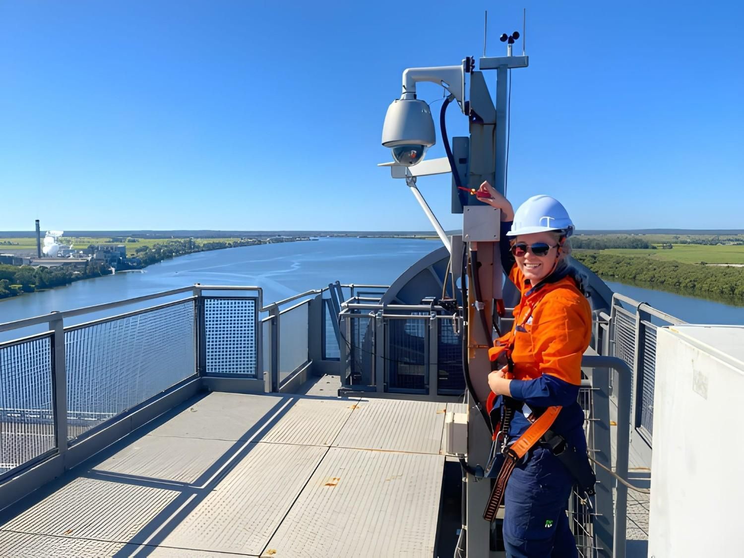 A Woman in Safety Gear on Tower, Adjusting Equipment — McGrath Electrical & Data in South Grafton, NSW