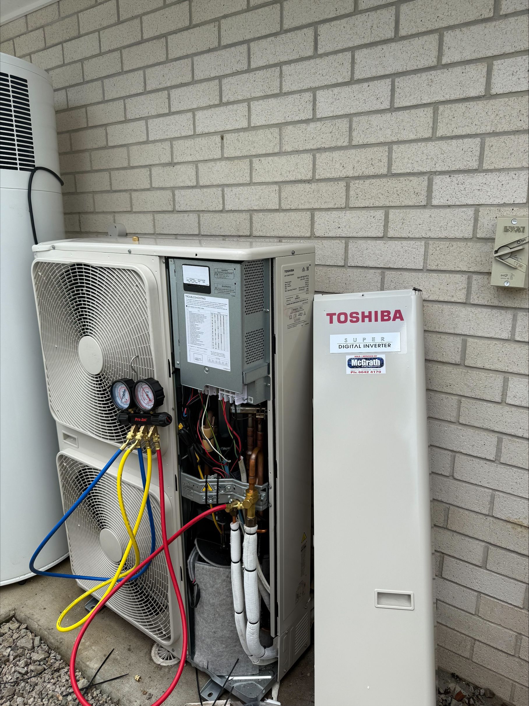 A Man on a Lift Working on Air Conditioning Units on a Red Building — McGrath Electrical & Data in South Grafton, NSW