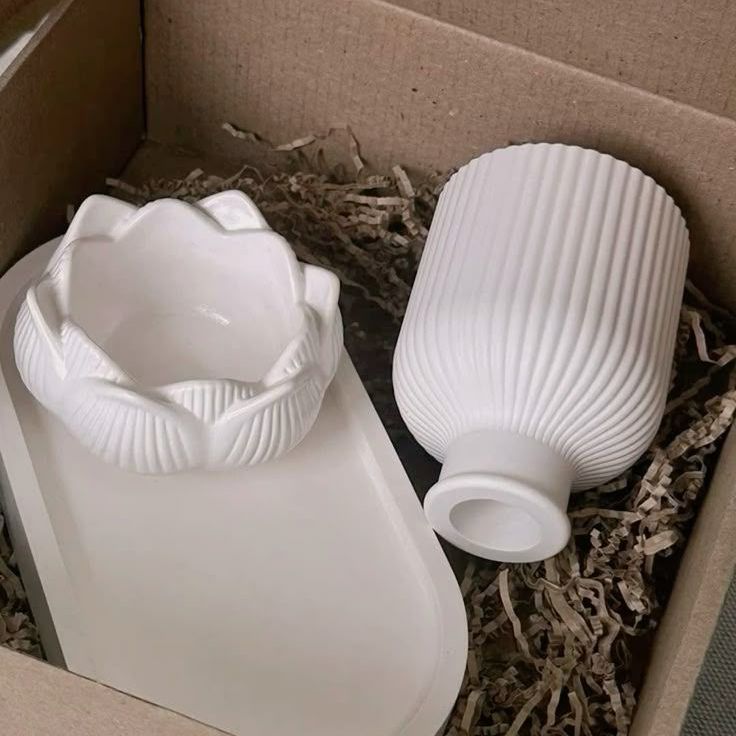 Tres cuencos blancos con forma de loto rodeados de ramitas de lavanda púrpura sobre una superficie blanca texturizada.