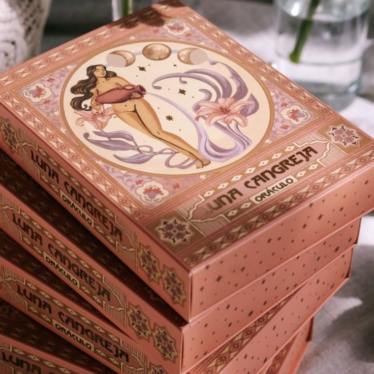 Baraja de tarot en caja con cartas ilustradas: mujer, flores y texto en español sobre fondos pastel.