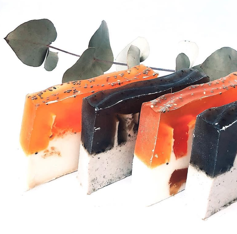 Tres pastillas de jabón de colores con una rama de eucalipto y un clip rojo.