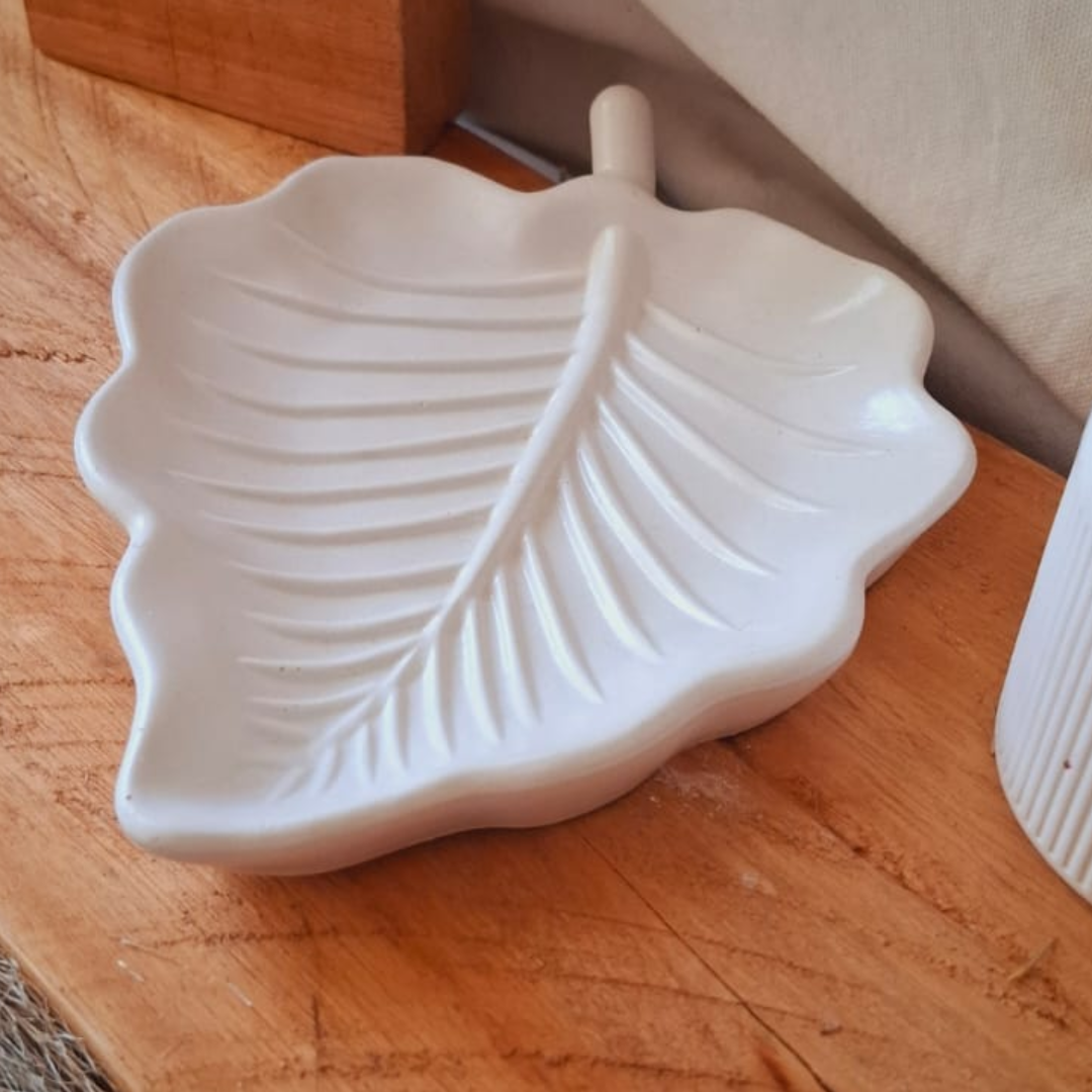 Plato blanco con forma de hoja y ramitas de lavanda sobre un mantel blanco texturizado.