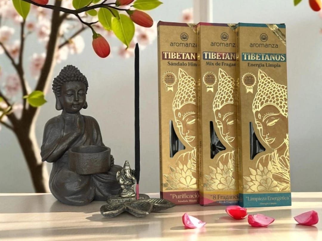 Fila de cajas de incienso con ilustraciones doradas de una figura meditando, sobre un estante de madera.