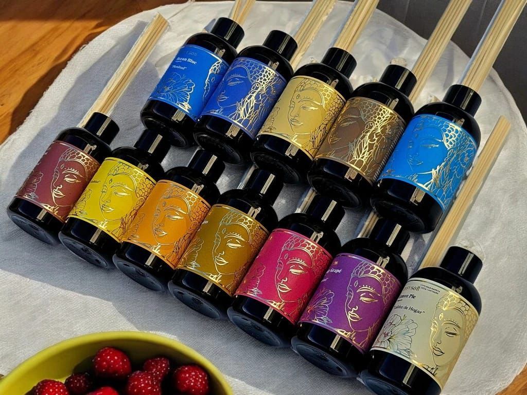 Cinco coloridos difusores de aceites esenciales con varillas de caña sobre una mesa de madera.