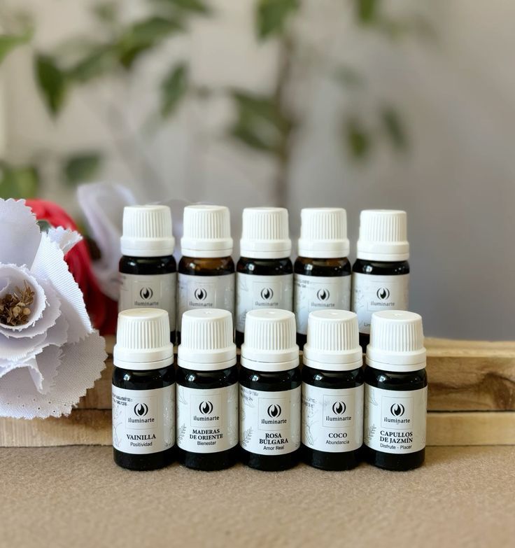 Mano sosteniendo un frasco de aceite esencial sobre un difusor, con cuatro frascos delante.