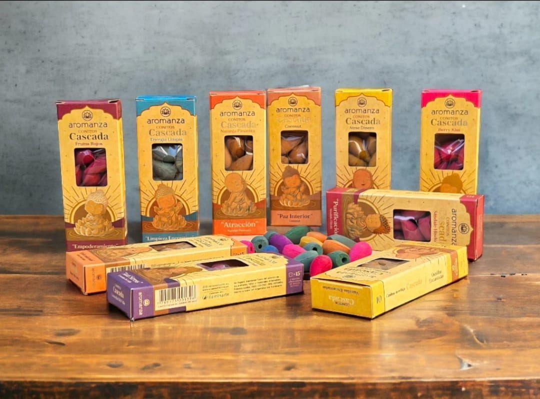 Un porta incienso con forma de Buda del que brota humo en cascada, junto a una caja de conos de incienso de lavanda.