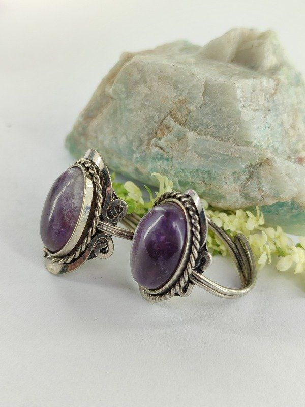 Dos anillos de plata con engastes ovalados de piedras preciosas moradas en espiral.