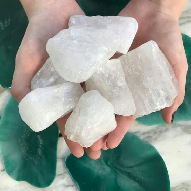 Manos sosteniendo una pila de cristales de cuarzo blanco y opaco