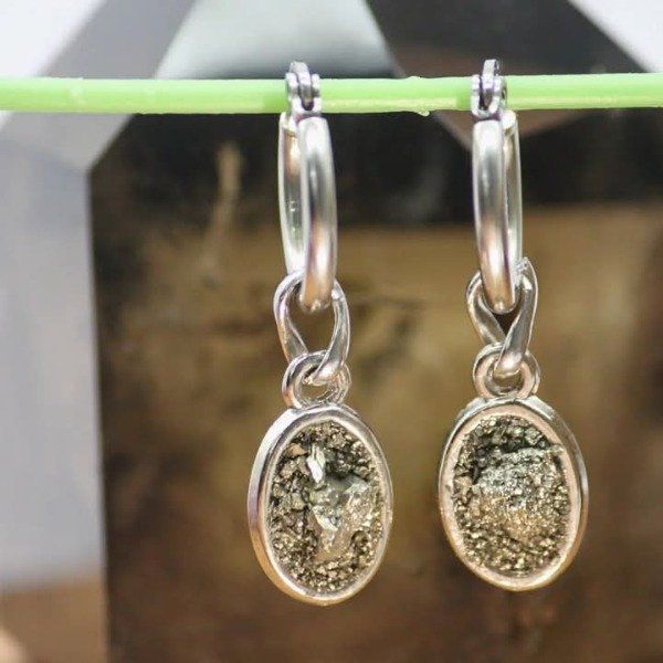Pendientes de aro de plata con colgantes de piedras ovaladas moteadas en oro que cuelgan de un nudo.