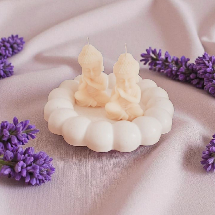 Dos velas retorcidas de color crema en un candelabro blanco