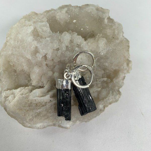 Pendientes de turmalina negra sobre fondo de piedra blanca.