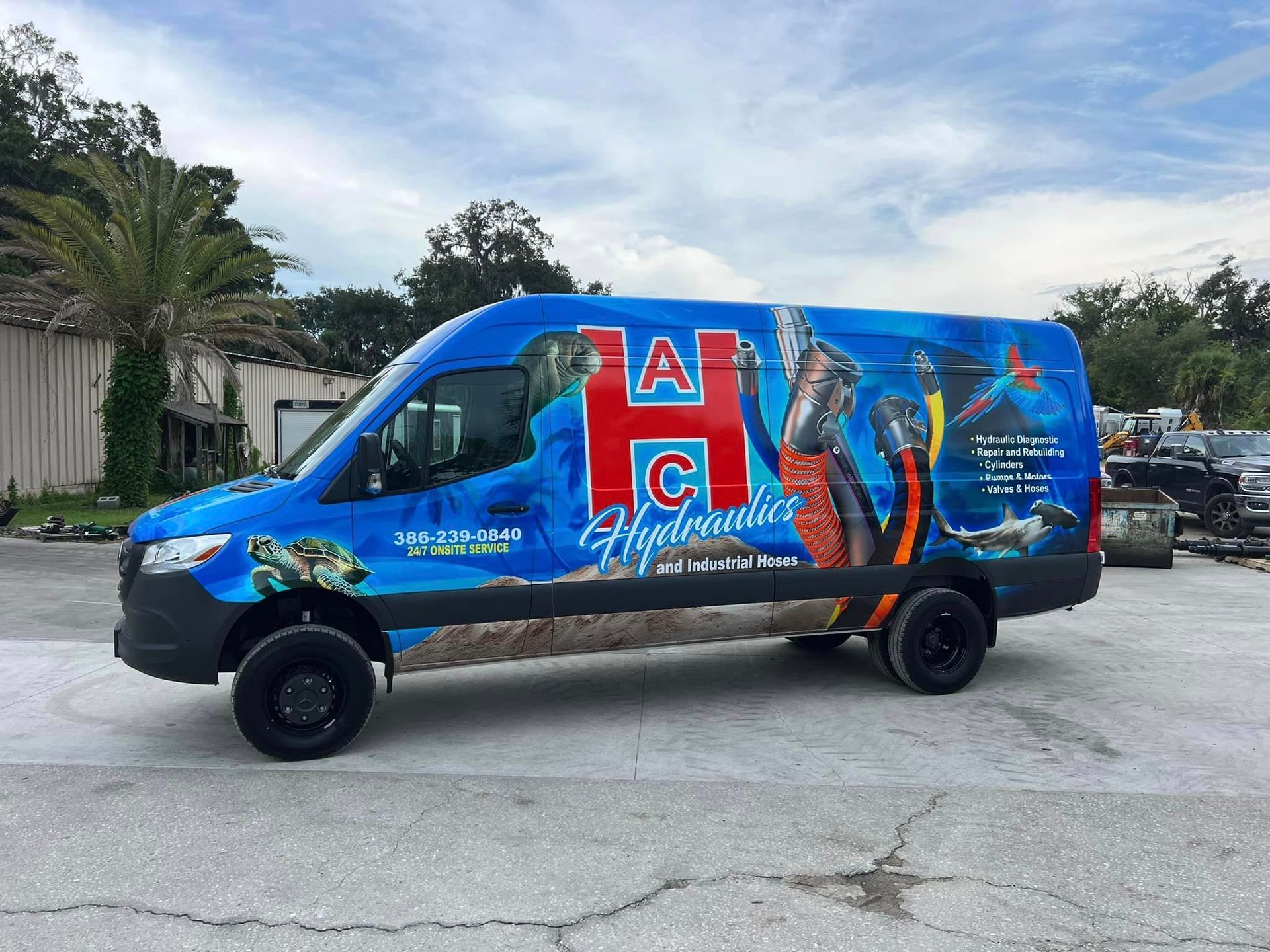 A blue van is parked in a parking lot in front of a building.